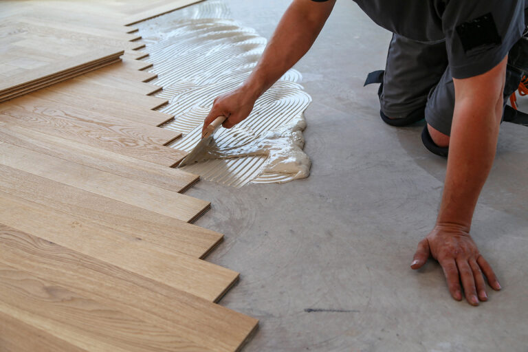 Installer fitting wooden floor boards during a professional hardwood floor installation
